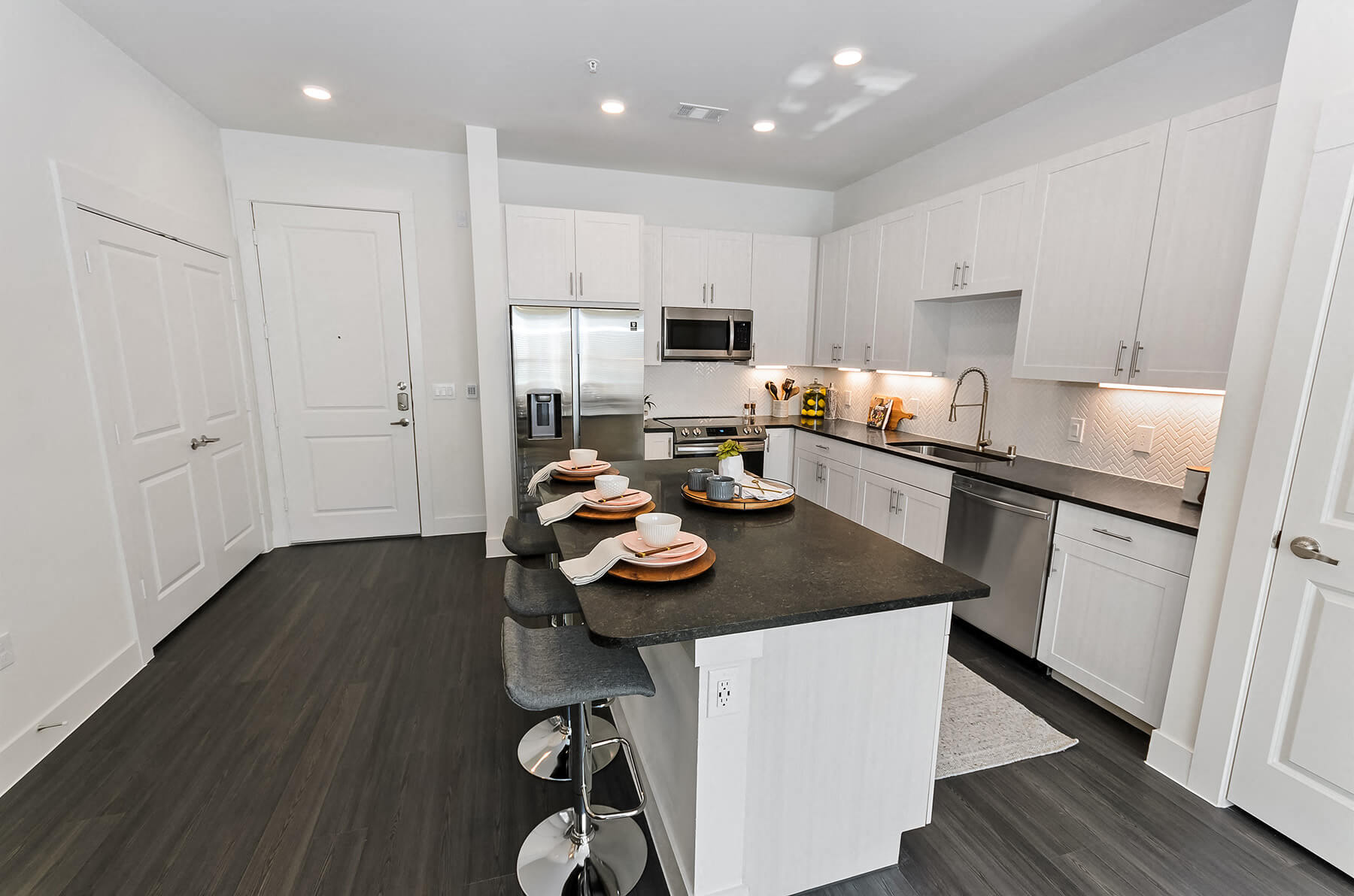 A modern kitchen with dark cabinets with a kitchen island at the Opal Legacy Central in Plano, Texas.